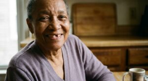 Senior smiling with missing tooth gap in natural home lighting